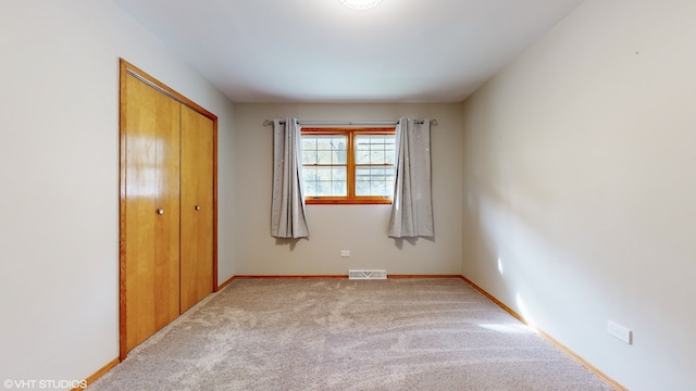 unfurnished bedroom with light carpet and a closet