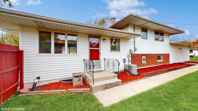 tri-level home featuring a front yard and cooling unit