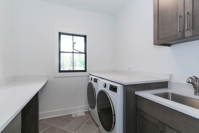 laundry room featuring sink, dark tile patterned flooring, cabinets, and washing machine and clothes dryer