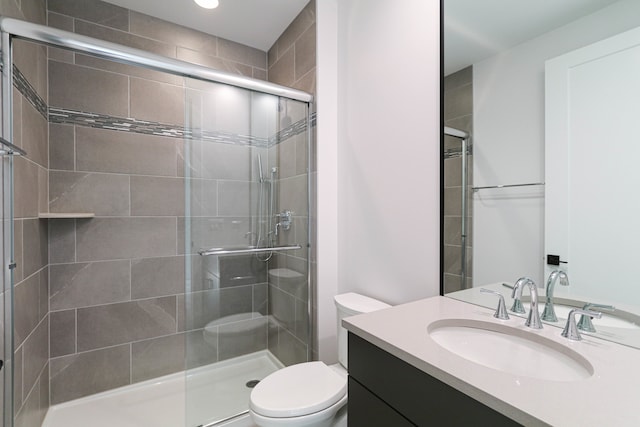 bathroom featuring a shower with shower door, vanity, and toilet