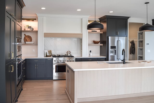 kitchen with pendant lighting, high end appliances, and light hardwood / wood-style flooring