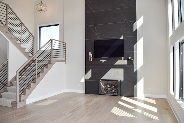 living room featuring a towering ceiling, hardwood / wood-style floors, a fireplace, and a notable chandelier