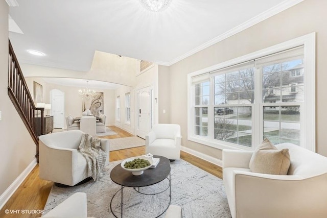 living room with light wood-type flooring, crown molding, and a notable chandelier