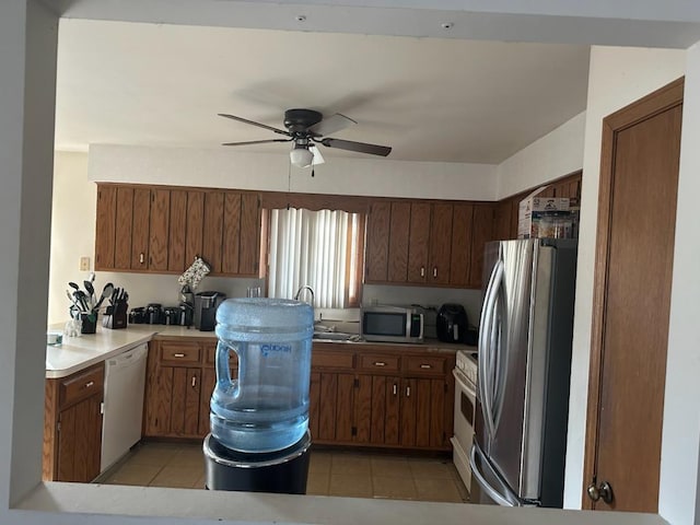 kitchen with stainless steel appliances, sink, light tile patterned floors, and ceiling fan