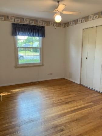 unfurnished bedroom with a closet, hardwood / wood-style floors, and ceiling fan