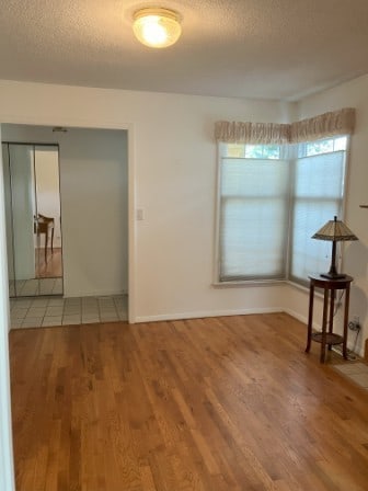 unfurnished room with wood-type flooring and a textured ceiling