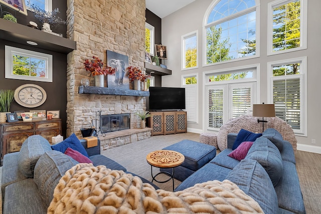 living room featuring a high ceiling, a fireplace, wood finished floors, and baseboards