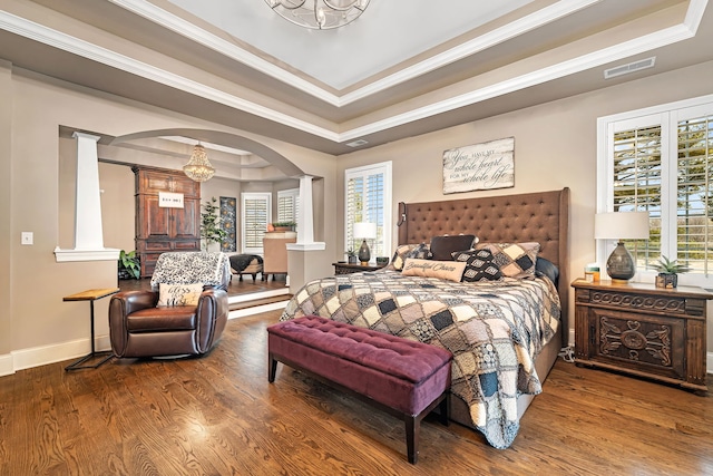 bedroom featuring a tray ceiling, visible vents, multiple windows, and wood finished floors