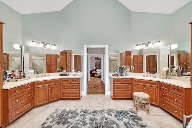 full bathroom featuring tile patterned flooring, high vaulted ceiling, a tile shower, and a sink
