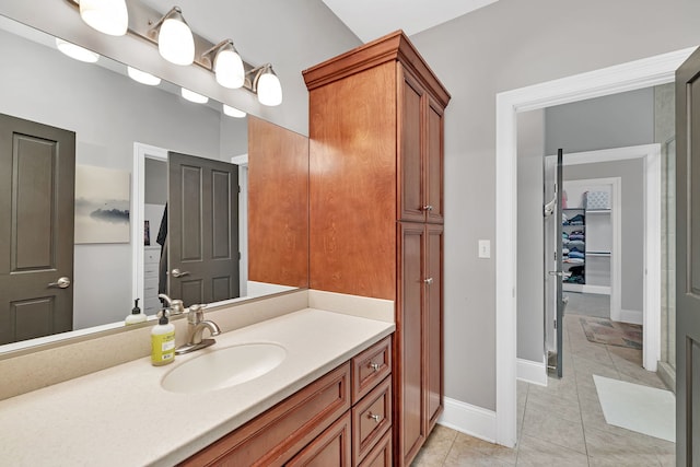 bathroom featuring a spacious closet, vanity, baseboards, and tile patterned floors