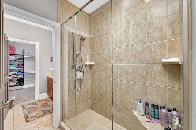 bathroom with a spacious closet, a stall shower, tile patterned flooring, and vanity