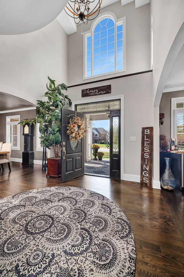 entrance foyer with a high ceiling, baseboards, arched walkways, and wood finished floors
