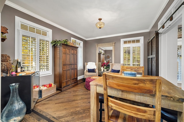 dining space featuring wood finished floors, crown molding, and a barn door