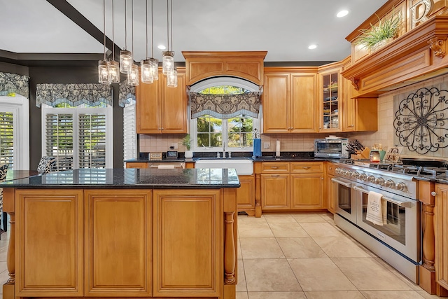 kitchen featuring dark stone counters, a kitchen island, custom exhaust hood, double oven range, and a sink