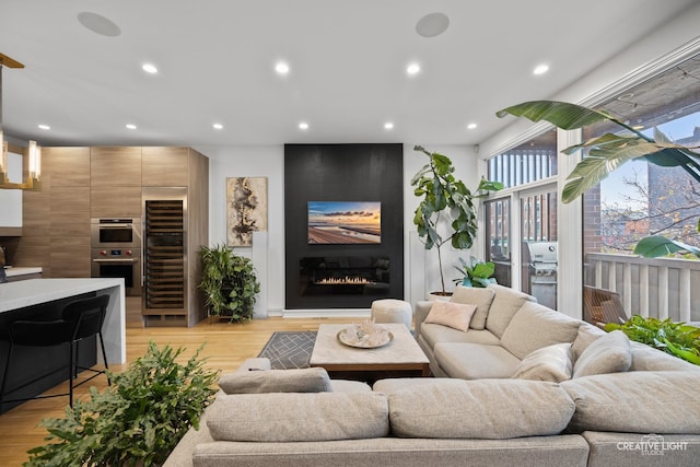 living room with a fireplace, light hardwood / wood-style floors, and beverage cooler