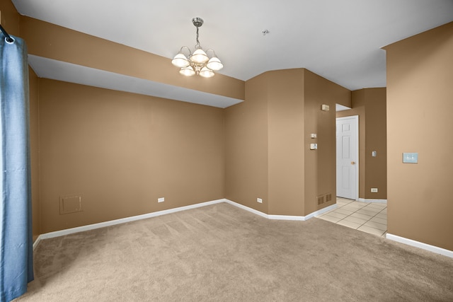 empty room featuring light carpet and a notable chandelier