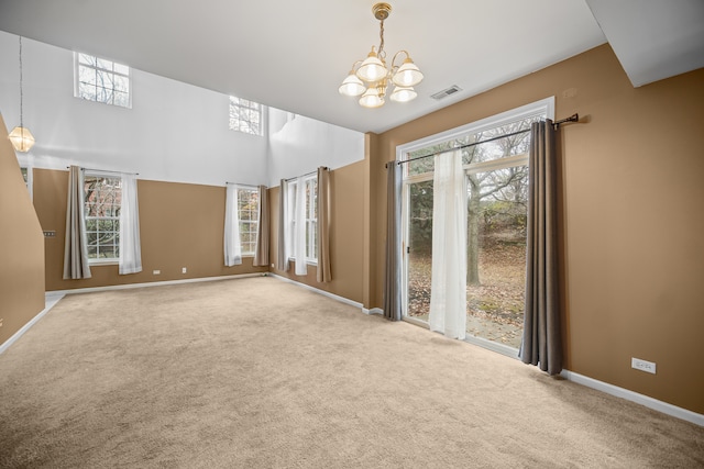 empty room featuring a wealth of natural light, a notable chandelier, and carpet