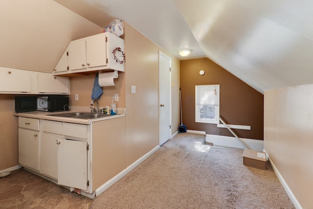 kitchen with white cabinets, light colored carpet, sink, and vaulted ceiling