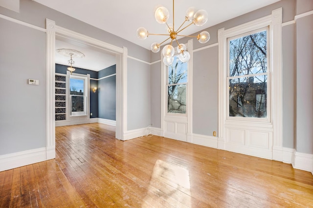 unfurnished dining area featuring hardwood / wood-style floors and a chandelier