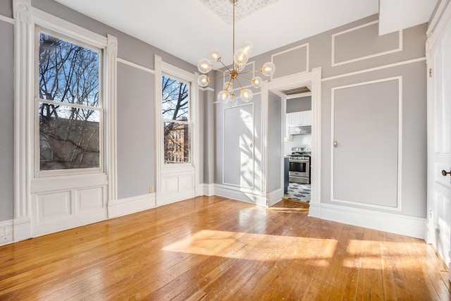 unfurnished dining area with hardwood / wood-style floors and a notable chandelier