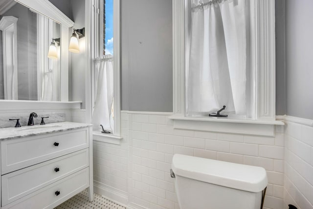 bathroom with vanity, toilet, and tile walls