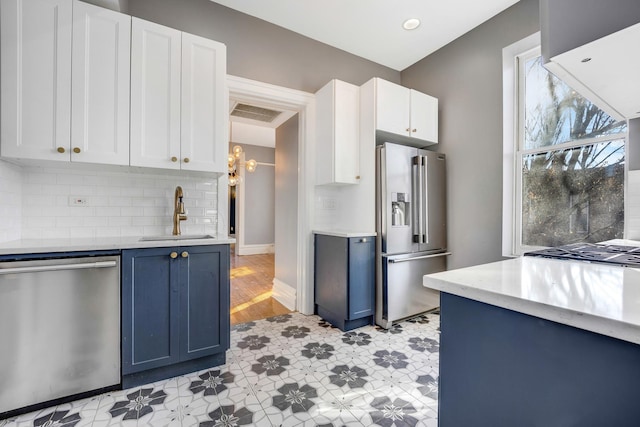 kitchen with white cabinets, blue cabinets, sink, tasteful backsplash, and stainless steel appliances