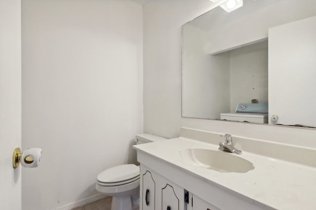 bathroom with toilet, vanity, and washer / dryer