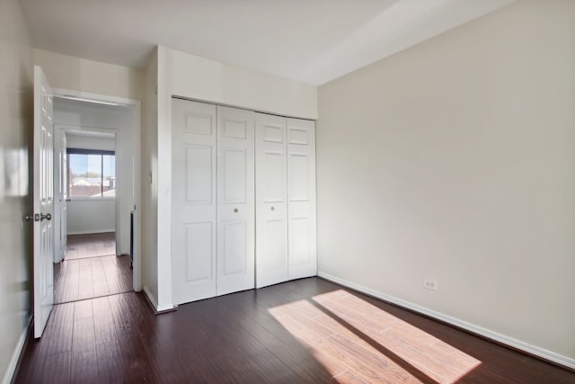 unfurnished bedroom featuring dark hardwood / wood-style flooring and a closet