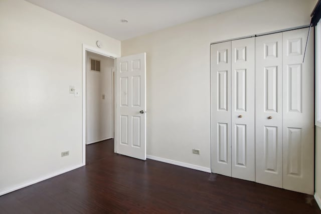 unfurnished bedroom featuring dark wood-type flooring and a closet