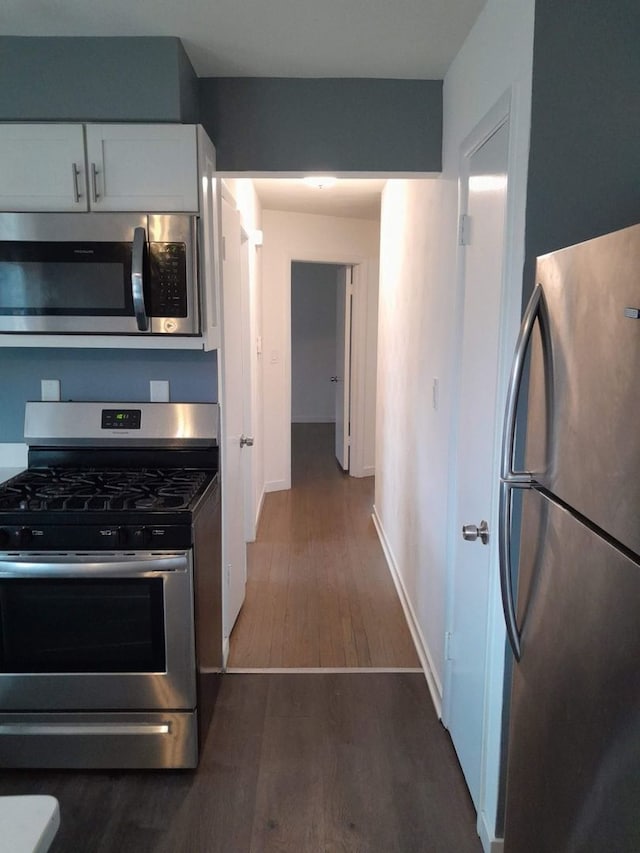 kitchen with white cabinets, dark hardwood / wood-style flooring, and appliances with stainless steel finishes