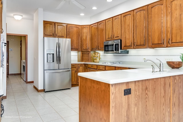 kitchen featuring sink, light tile patterned floors, ceiling fan, appliances with stainless steel finishes, and kitchen peninsula