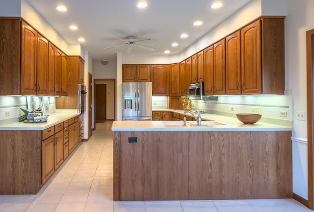 kitchen with appliances with stainless steel finishes, sink, decorative backsplash, ceiling fan, and kitchen peninsula