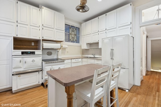 kitchen with light wood-type flooring, sink, paneled fridge, and white cabinets