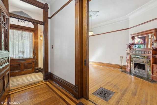 foyer with a brick fireplace, crown molding, and hardwood / wood-style floors