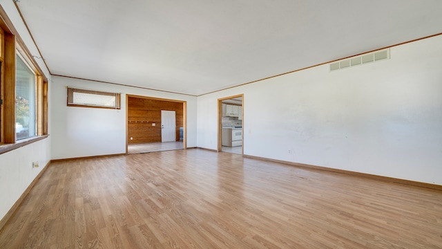 empty room with light wood-type flooring and crown molding