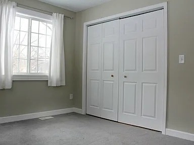 unfurnished bedroom featuring light colored carpet and a closet