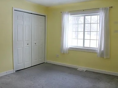 unfurnished bedroom with light colored carpet and a closet