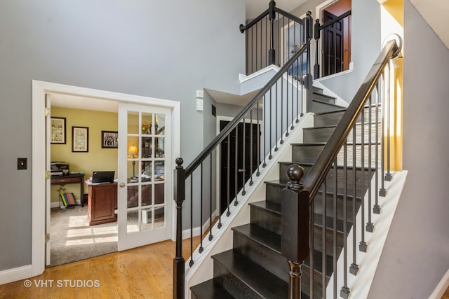 stairs with french doors and hardwood / wood-style flooring