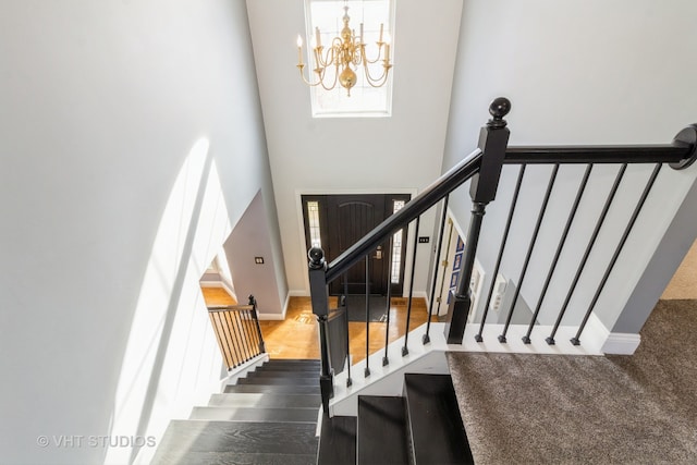 staircase with an inviting chandelier and wood-type flooring