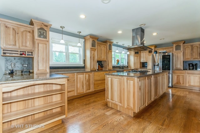 kitchen featuring island exhaust hood, stainless steel appliances, a kitchen island, hanging light fixtures, and dark stone countertops