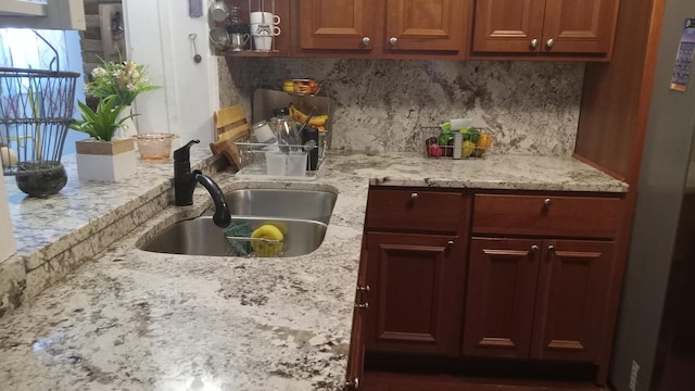 kitchen with decorative backsplash, light stone counters, and sink