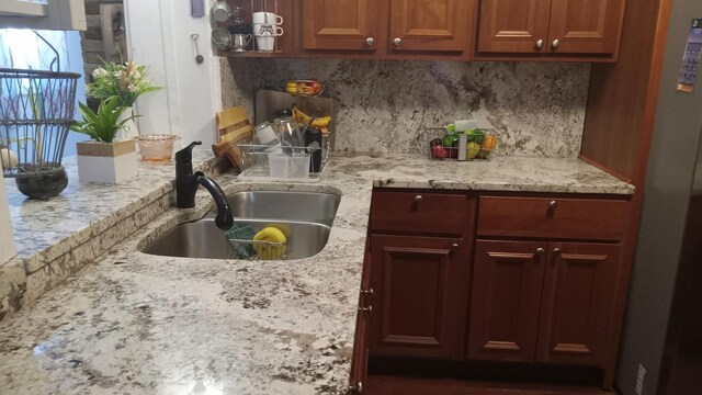 kitchen with light stone countertops, backsplash, and sink