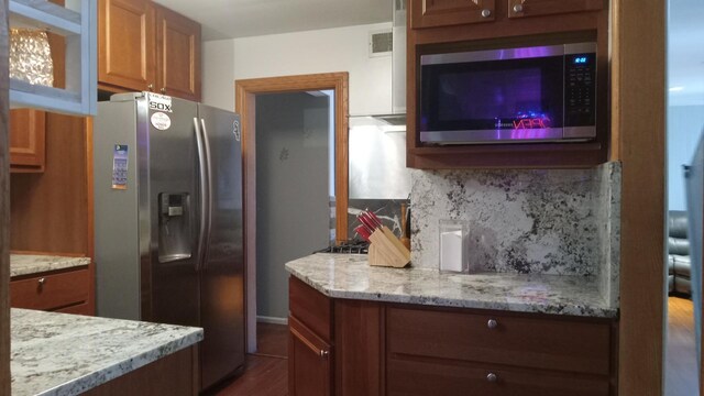 kitchen with light stone countertops, decorative backsplash, and stainless steel appliances