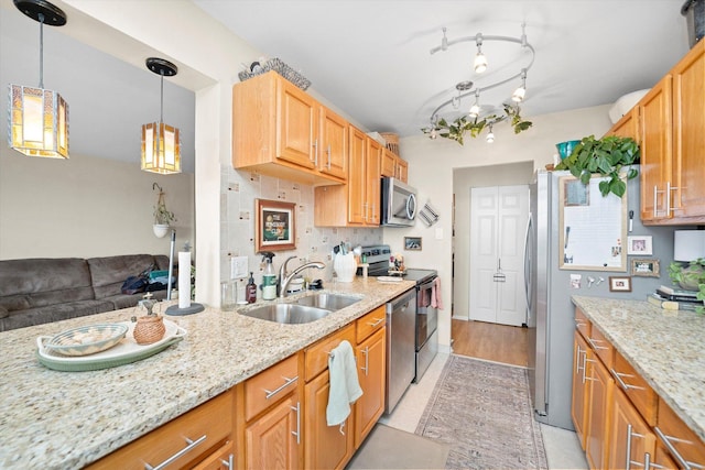 kitchen featuring sink, light stone countertops, appliances with stainless steel finishes, tasteful backsplash, and decorative light fixtures