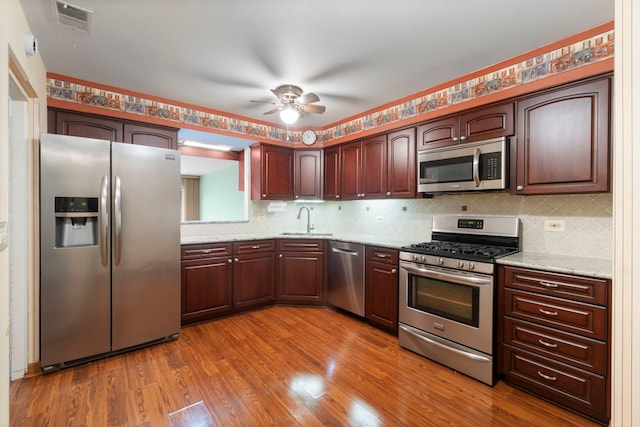 kitchen with decorative backsplash, appliances with stainless steel finishes, ceiling fan, sink, and hardwood / wood-style flooring