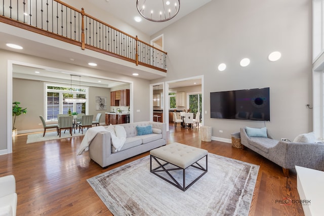 living room with a high ceiling, dark hardwood / wood-style floors, and an inviting chandelier