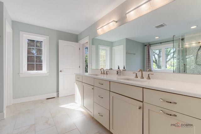 bathroom featuring vanity, a healthy amount of sunlight, and a shower with shower door