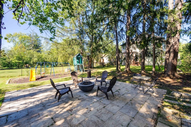 view of patio with a playground and a fire pit