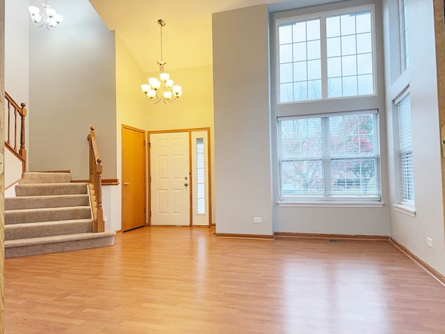 foyer entrance with a chandelier, a high ceiling, and light wood-type flooring