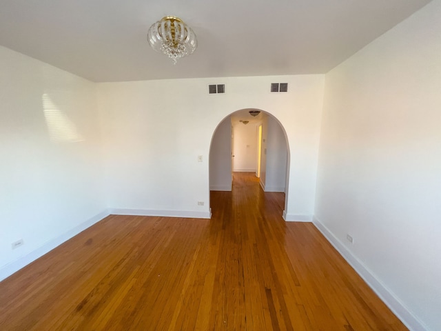 empty room featuring hardwood / wood-style floors and an inviting chandelier